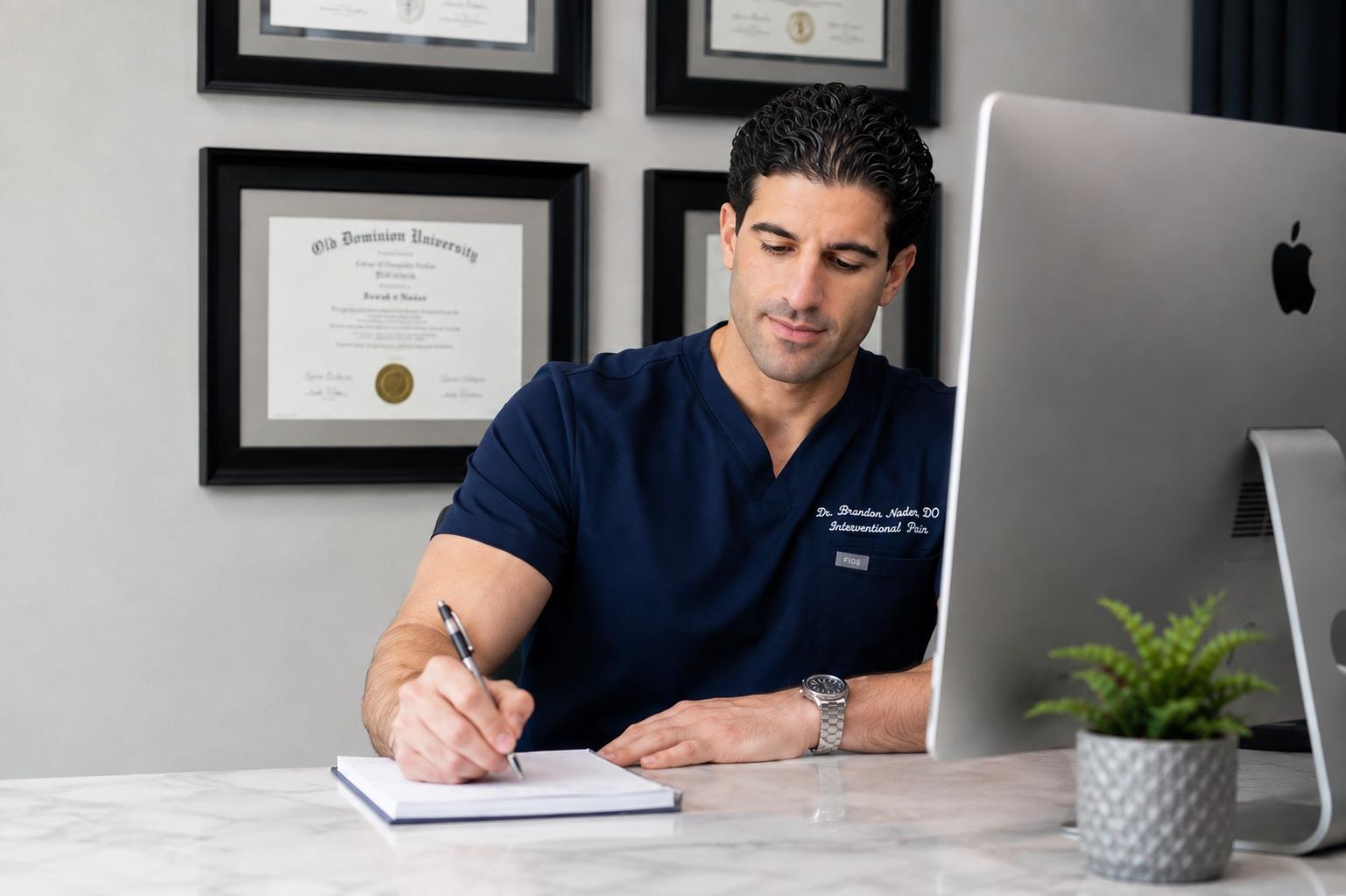 Dr. Brandon Nader, DO, at his desk